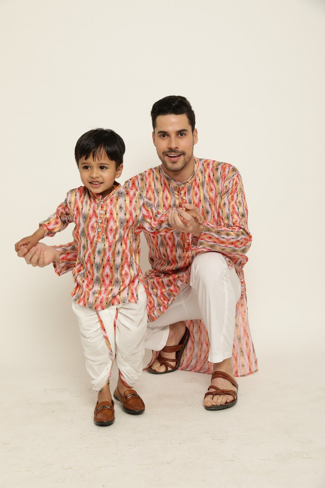 Coordinated father-son ethnic kurta pajama combo in bright orange ikat print