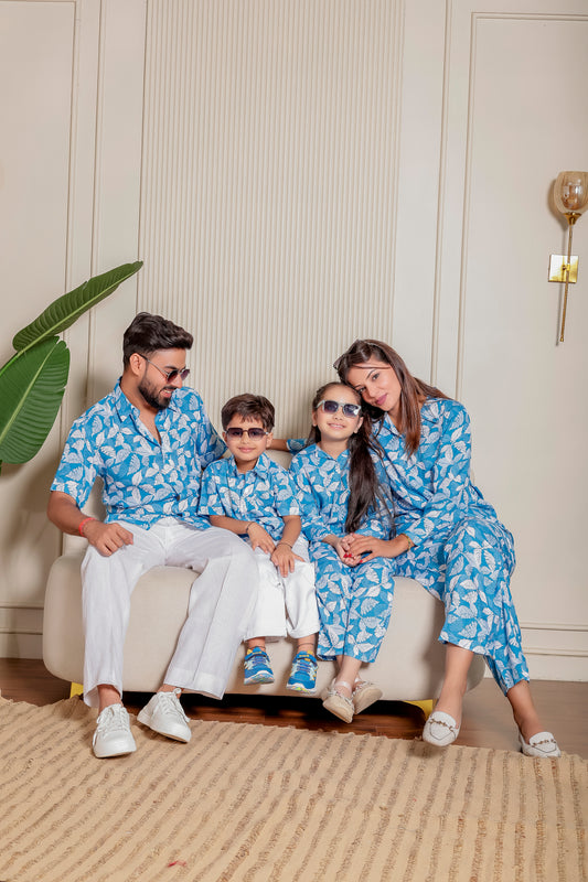 Coastal Cool family matching outfits in cotton with blue leafy print—father in shirt, mother in co-ord set, kids in matching styles. Ideal for beach holidays, family photoshoots, and festive twinning.